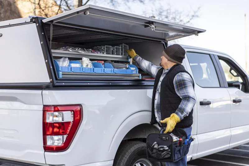 A worker accessing a large side door on an Adrian truck cap